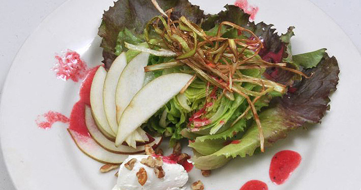 A composed salad of mixed greens, thin apple slices, crisp shallots and a quenelle of soft cheese.